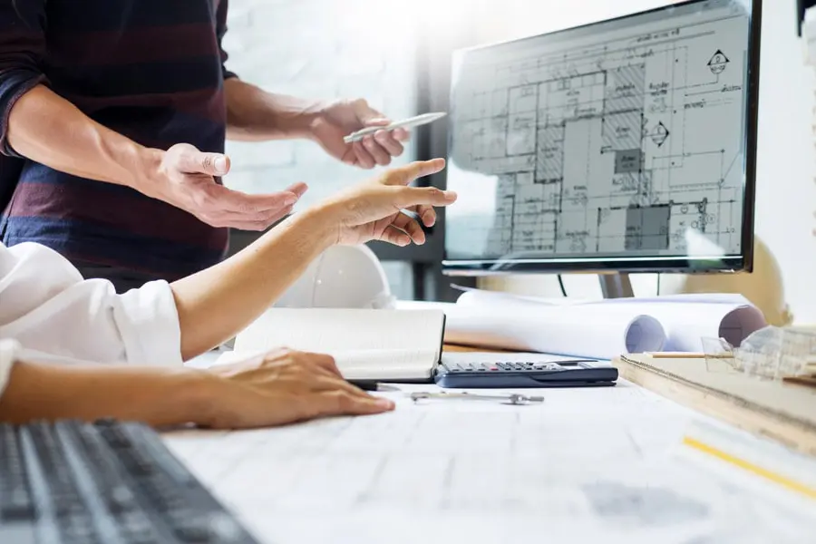 Builders-Risk-Insurance-Builder-with-Plans-Looking-at-a-Computer-min